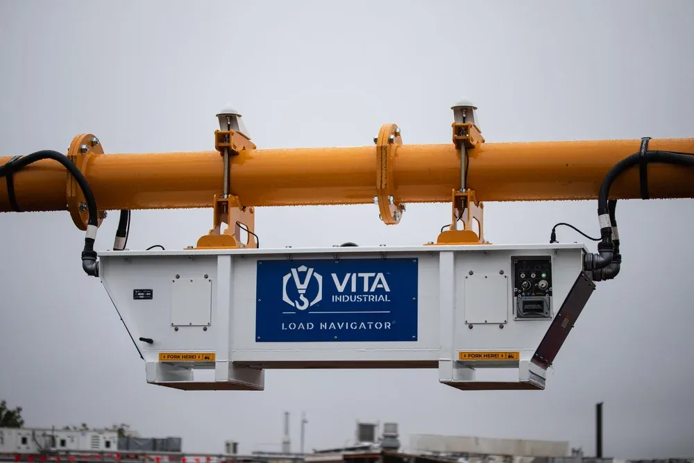 Construction crane lift with orange boom and white load navigator platform on a cloudy day.