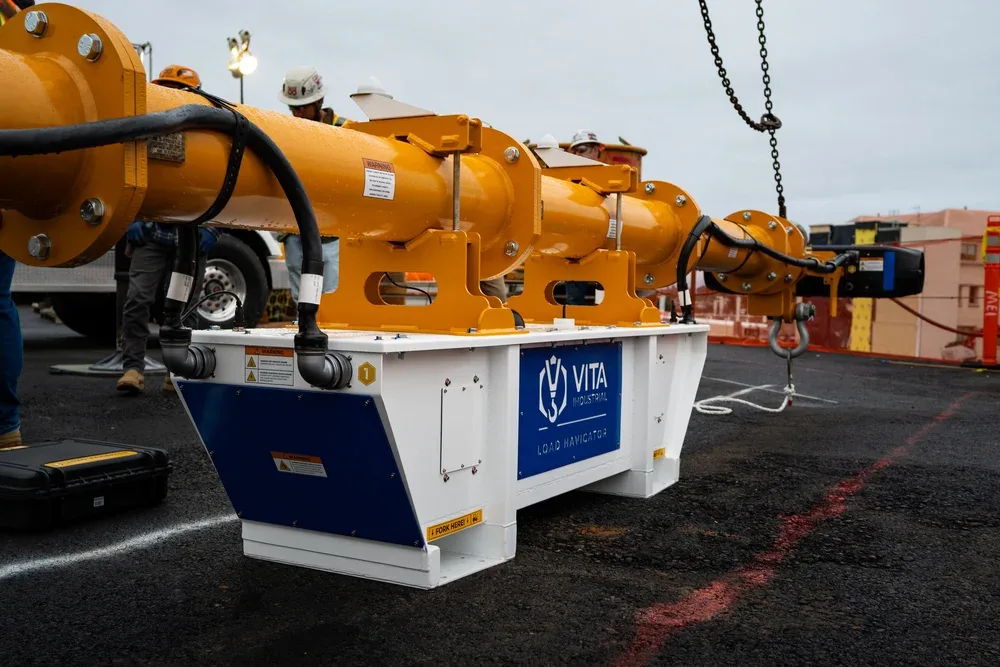 Heavy construction equipment labeled 'Load Navigator' being installed on a construction site with workers and overcast sky.
